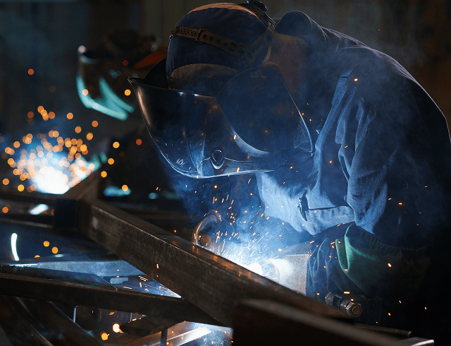 Welder working with sparks and protective gear.
