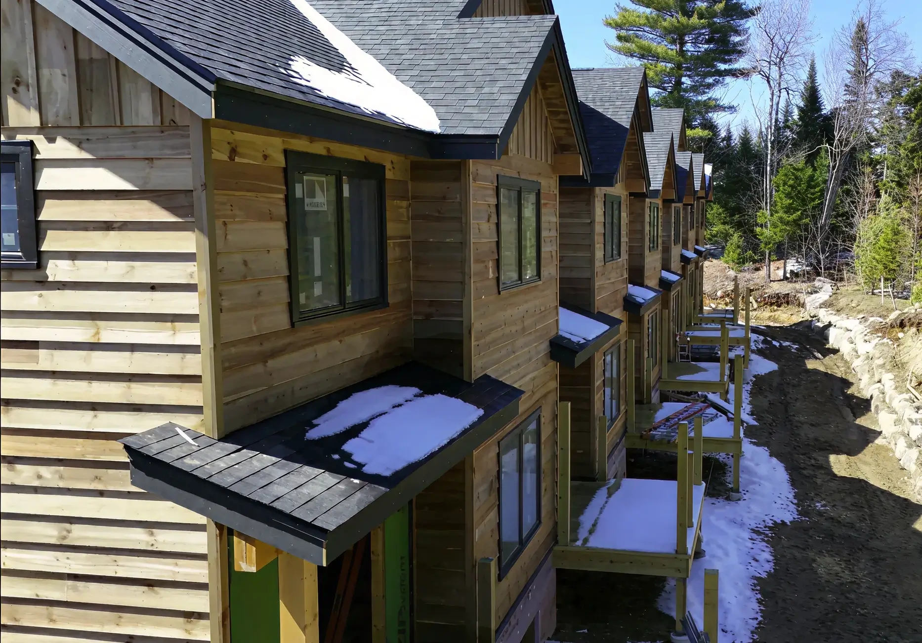 Row of wooden cabins with snowy roofs.