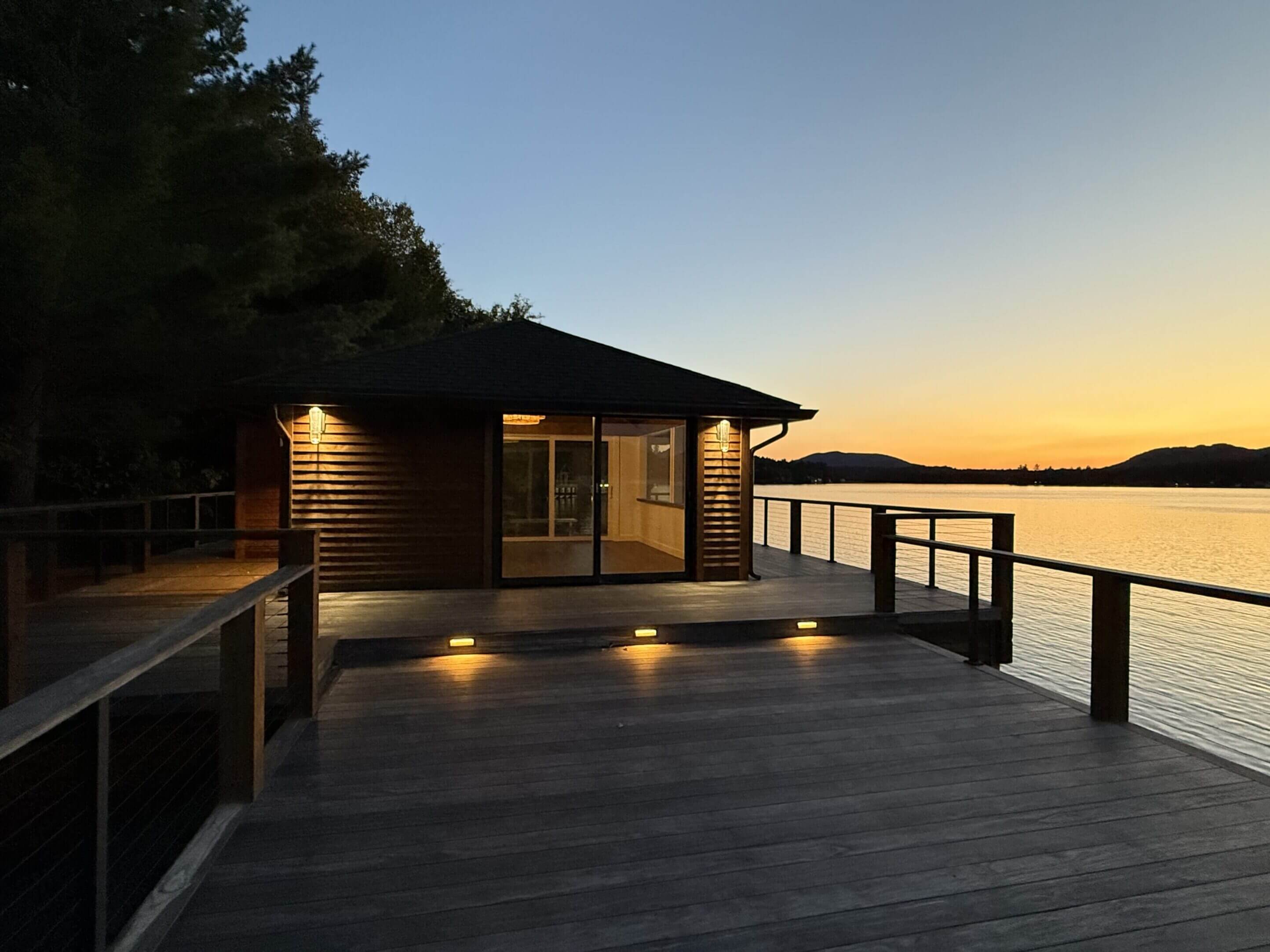 Lakeside cabin at sunset with deck.