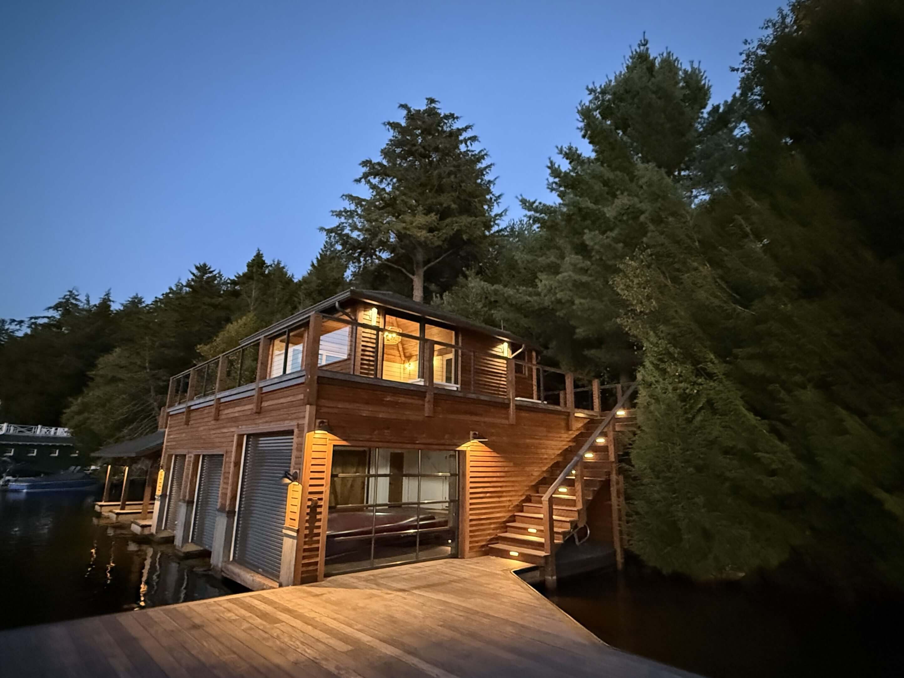 Wooden lake house surrounded by trees at dusk.