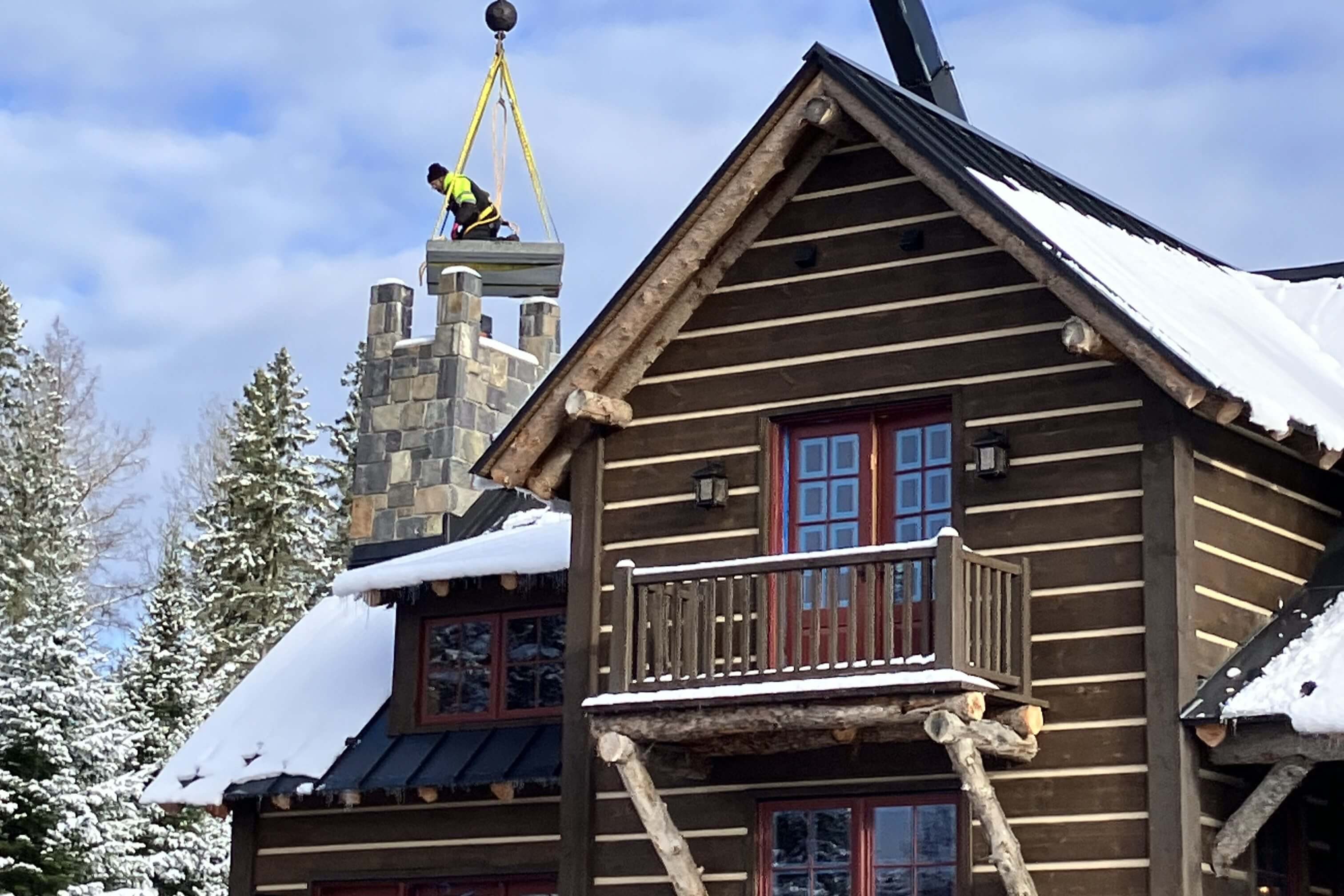 Log cabin with snowy roof and chimney.